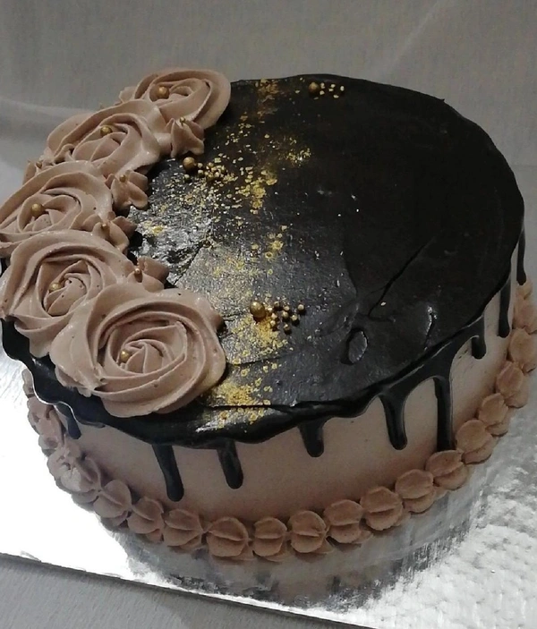 Deep Creamy Choclate Cake Topped With Golden Sprinkles And Semi Brown Flowers