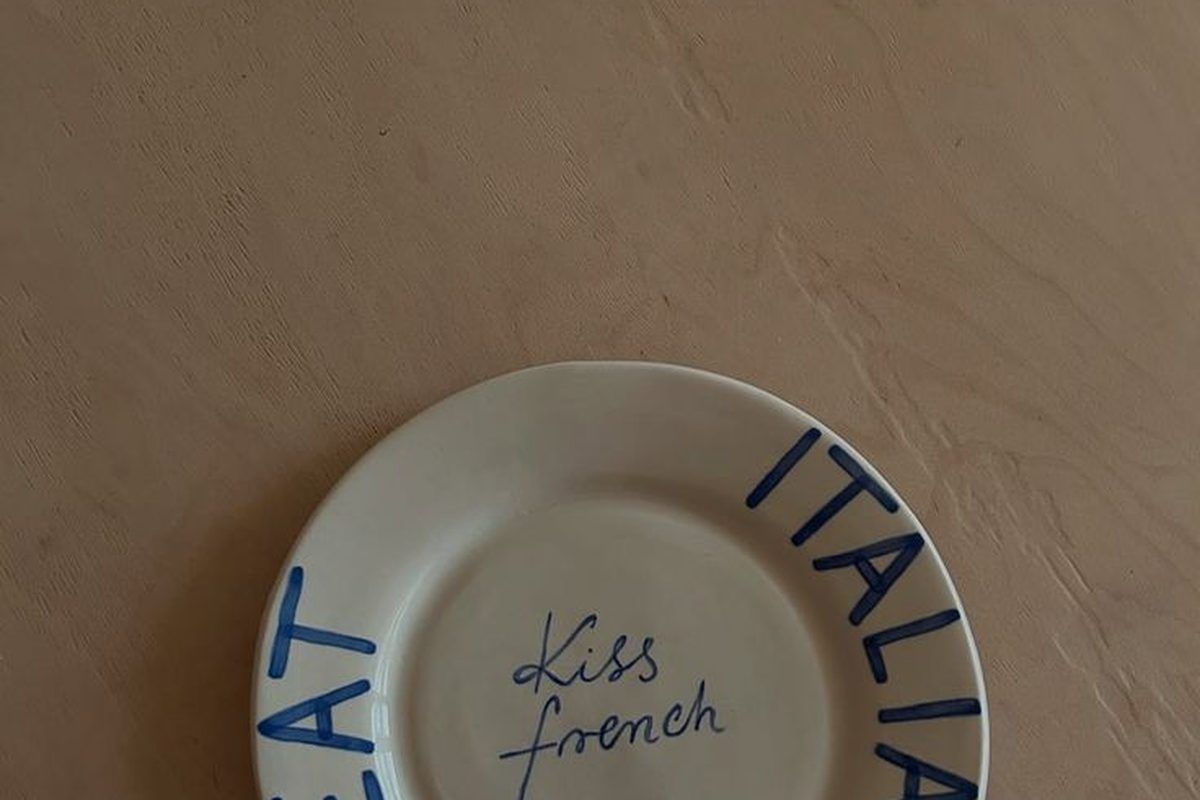 A Smirk Living plate held in hand against a raw plaster wall