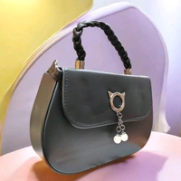 This black faux leather sling bag features a unique cat-ear hardware accent and a braided top handle.