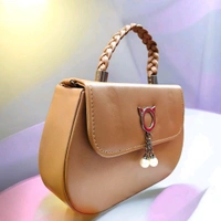 This BROWN faux leather sling bag features a unique cat-ear hardware accent and a braided top handle.