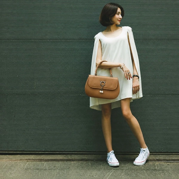 This BROWN faux leather sling bag features a unique cat-ear hardware accent and a braided top handle.