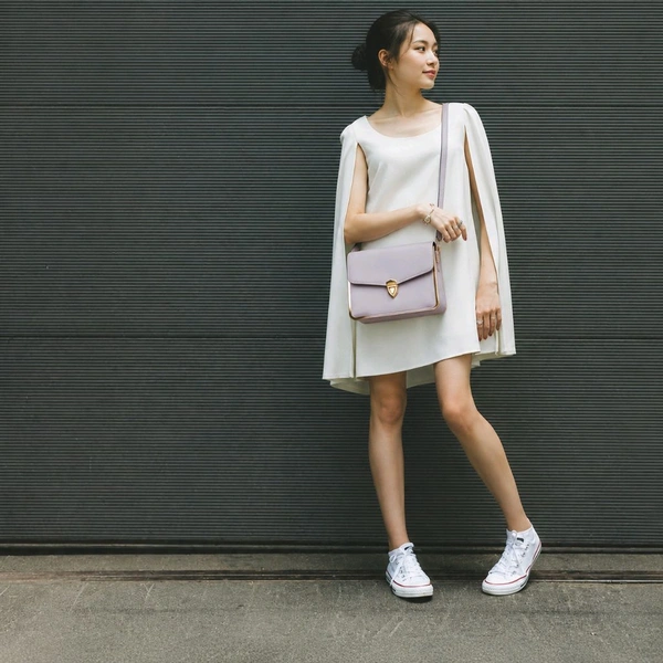 This Light Purple faux leather crossbody satchel by The Rare Bird features a metallic gold frame accent and a turn lock closure.