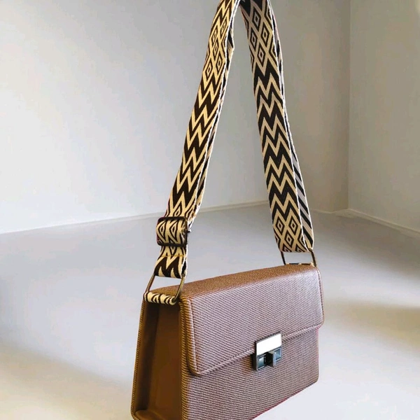 This textured brown crossbody bag features a patterned strap and a silver turn-lock closure.
