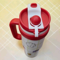 This red and white tumbler features a fruit-themed grid pattern, a prominent handle, and a flip-top lid
